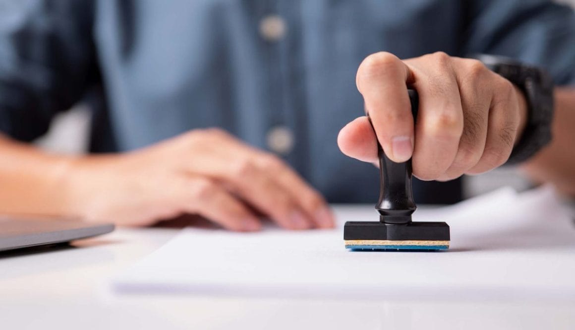 Close-up of a person's hand stamping on an approved application